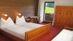 A wooden bed with white linens, a wooden wardrobe, a small table, and a chair. - Fertinghof (OBERAU)