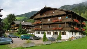 A multi-story wooden chalet with balconies, surrounded by lush greenery and mountains. - Fertinghof (OBERAU)