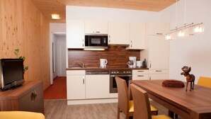 Una cocina moderna con armarios blancos, un microondas y un comedor con una mesa de madera y sillas amarillas.
