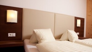 Una habitación de hotel con una cama, dos mesitas de noche y lámparas de pared.