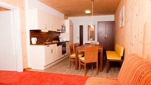Un espacio habitable compacto con comedor, cocina y una zona alfombrada de color rojo.