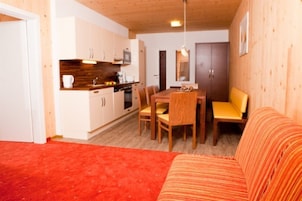 Un espacio habitable compacto con comedor, cocina y una zona alfombrada de color rojo.