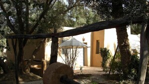 A rustic outdoor setting with a stone mill, wooden beams, and a traditional umbrella. - Dar Zitoune (Taroudant)