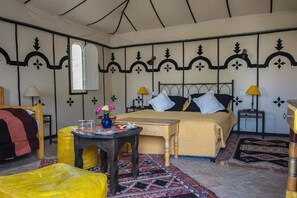Une chambre à coucher avec un lit, deux lampes de chevet, une petite table sur laquelle est posé un vase, et un tapis à motifs.