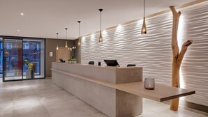 A modern reception desk with a minimalist design, a wooden accent wall, and pendant lighting. - Traube am See (Friedrichshafen)