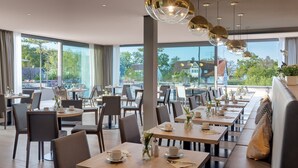 A modern restaurant with large windows, wooden tables, and chairs. - Traube am See (Friedrichshafen)