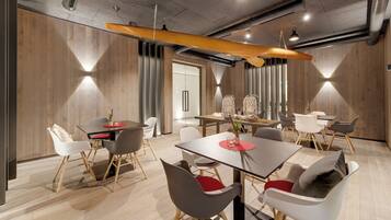 A modern dining area with wooden panel walls, a surfboard hanging from the ceiling, and contemporary furniture.
