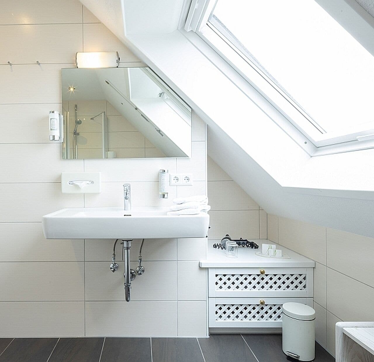 A modern bathroom with a skylight, white fixtures, and a tiled floor.