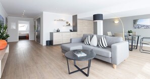 A modern living room with a grey sofa, a round coffee table, and a dining area with a table and chairs. - Traube am See (Friedrichshafen)
