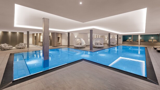 A large indoor swimming pool with lounge chairs and a modern interior design. - Traube am See (Friedrichshafen)