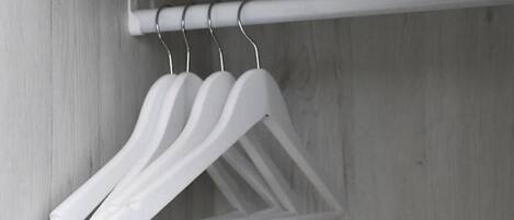 A closet with white hangers on a rod.