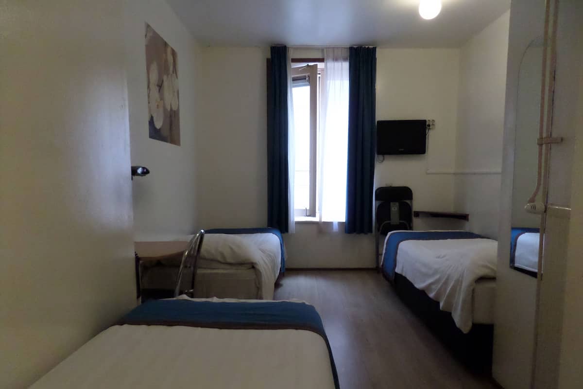 A hotel room with two beds, a desk, a chair, a television, and a window with curtains.