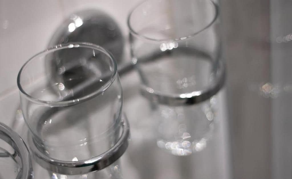 A close-up of clear glass tumblers with a reflective surface, arranged closely together.