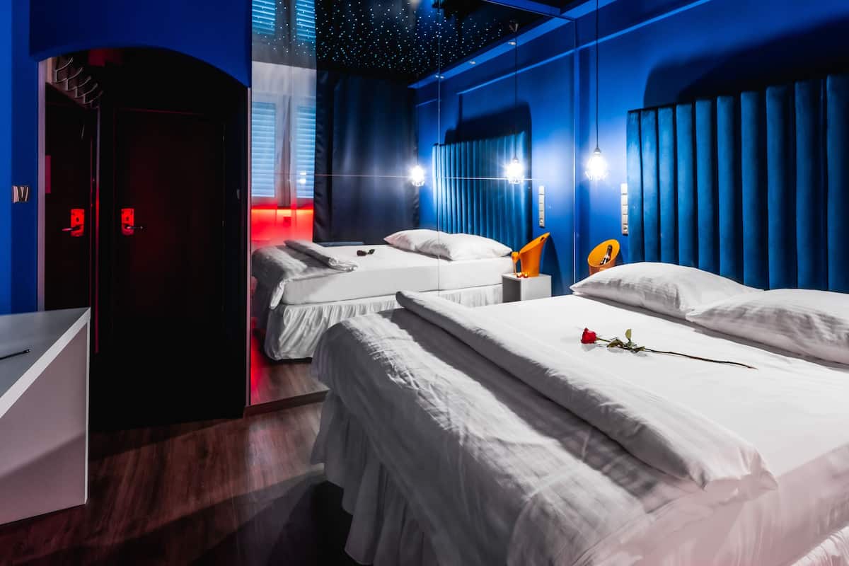 A hotel room with two beds, a nightstand, a chair, and a starry ceiling.