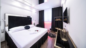 Et moderne hotelværelse med en stor seng, et sminkebord, et spejl og en garderobe med hængende tøj.