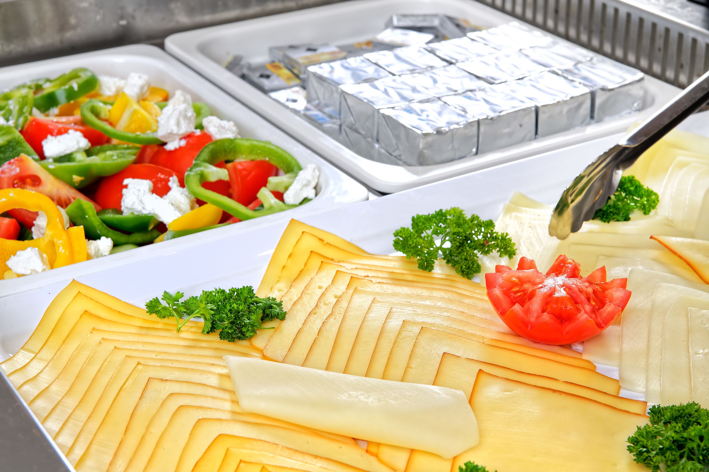 Un buffet con diversi cibi, tra cui formaggio, pomodori e peperoni.