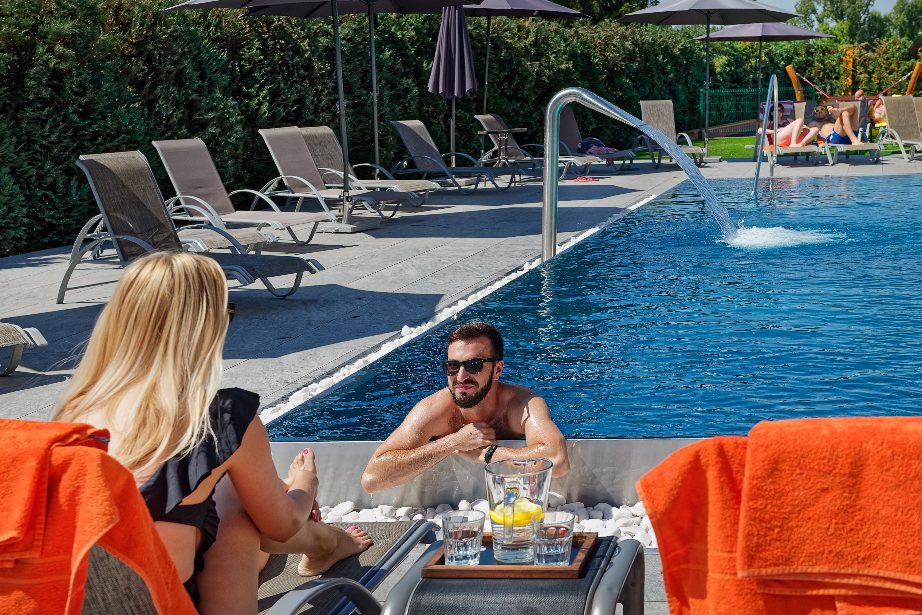 Zona de piscina con sillones de descanso y una mesa con bebidas.