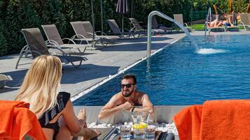 Zona de piscina con sillones de descanso y una mesa con bebidas.