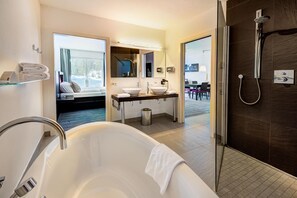 Ein modernes Badezimmer mit einer freistehenden Badewanne, einer Dusche und einem Waschtisch mit Spiegel.