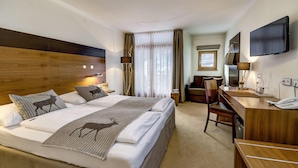Une chambre d’hôtel avec un grand lit, un bureau, une chaise, une télévision et une fenêtre avec des rideaux.