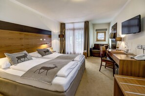 Une chambre d’hôtel avec un grand lit, un bureau avec une chaise, une télévision et une fenêtre avec des rideaux.