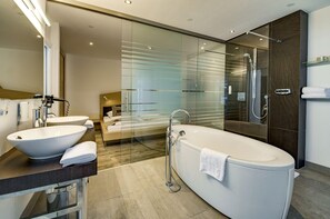 Une salle de bain moderne avec une baignoire sur pieds, deux vasques et une douche séparée par des parois en verre.