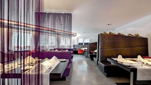 Un restaurant moderne avec un intérieur élégant, des tables hautes, des sièges confortables et un design contemporain.