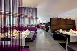 Un restaurant moderne avec un intérieur contemporain, des tables hautes, des sièges violets et une vue sur la rue.