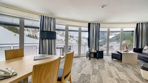 Habitació d'hotel amb una finestra gran que ofereix una vista panoràmica d'un paisatge cobert de neu.
