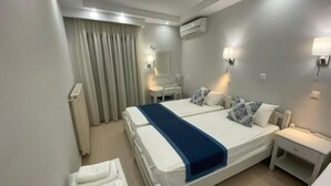 Habitación de hotel con una cama grande, dos mesitas de noche, un espejo y un ventanal con cortinas.