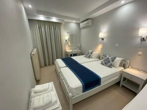 A hotel room with a large bed, two bedside tables, a mirror, and a window with curtains. - Ifestos Hotel (MIRINA)