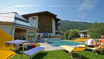 Relax by the pool surrounded by lush greenery and comfortable lounge chairs.