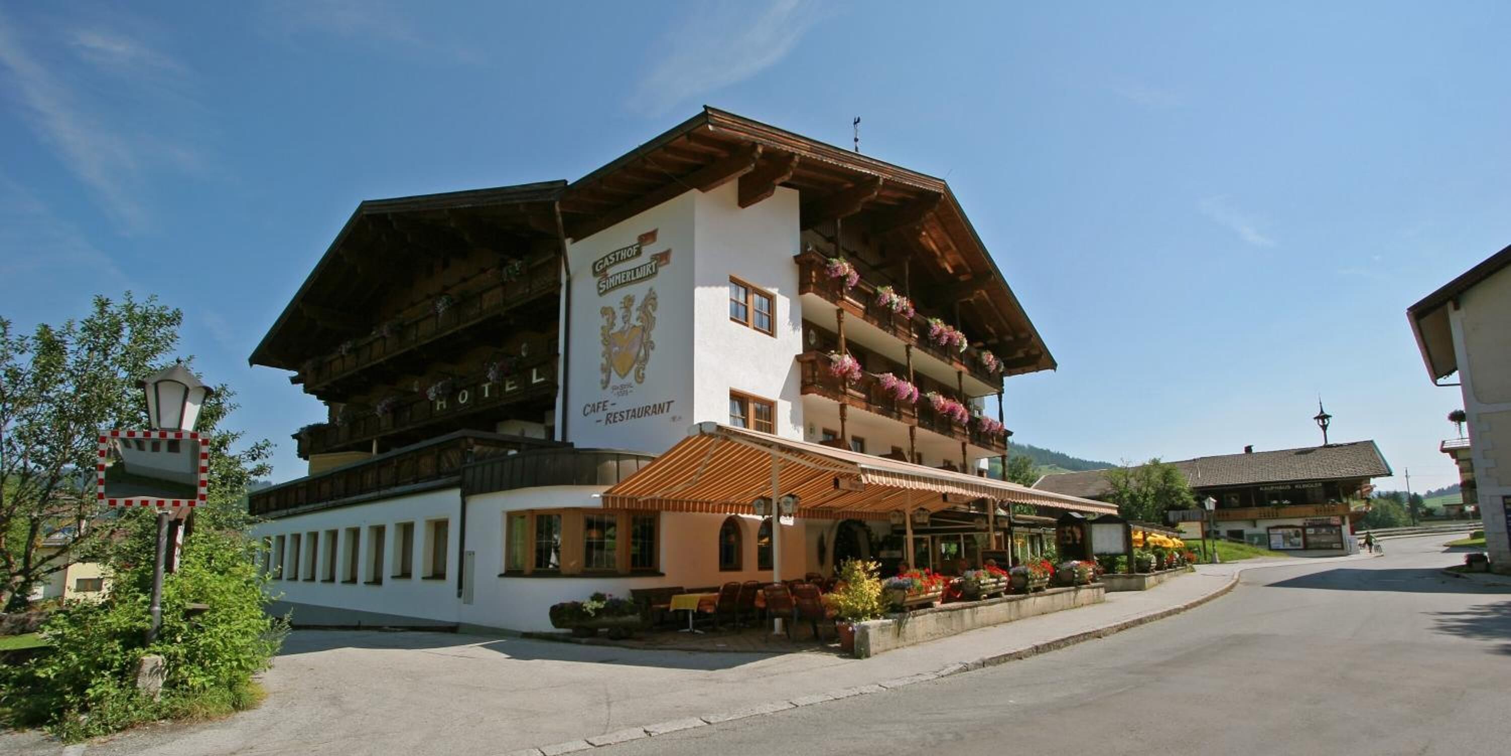 A traditional Alpine hotel with a cafe and restaurant on the ground floor, featuring wooden balconies with flower boxes.