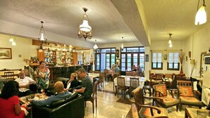 A spacious lobby with multiple seating areas, a bar, and large windows allowing natural light. - Pela Hotel (Lesvos)