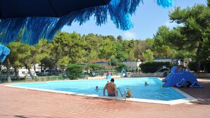 An outdoor swimming pool with a blue inflatable slide and a blue tent overhead. - Villaggio Capo Vieste Camping (Vieste)