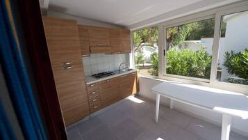 Une cuisine moderne avec des meubles en bois, une cuisinière à gaz et une grande fenêtre donnant sur un jardin.