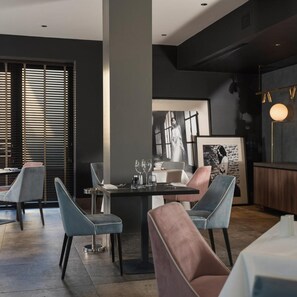 A modern dining area with a central table, chairs, and a bar area with a light fixture. - Hotel Tiffany's (Cervia)