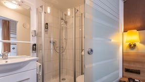 Ein modernes Badezimmer mit einer Duschkabine, einem Waschbecken mit Spiegel und einer Toilette.