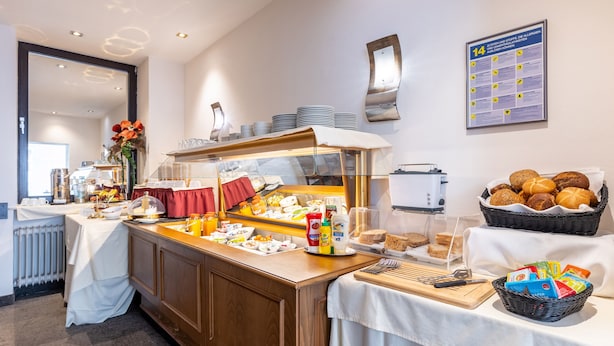 Ein Buffet mit verschiedenen Speisen, eine Kaffeestation und ein an der Wand befestigtes Informationsschild.