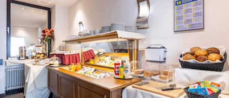 A buffet setup with various food items, a coffee station, and a wall-mounted informational poster.