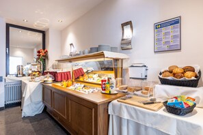 A buffet setup with various food items, a coffee station, and a wall-mounted informational poster. - Trip Inn Hotel Hamm Koblenz (Koblenz)