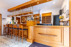 Una cocina moderna con taburetes de madera, una barra empotrada y un ventanal grande.