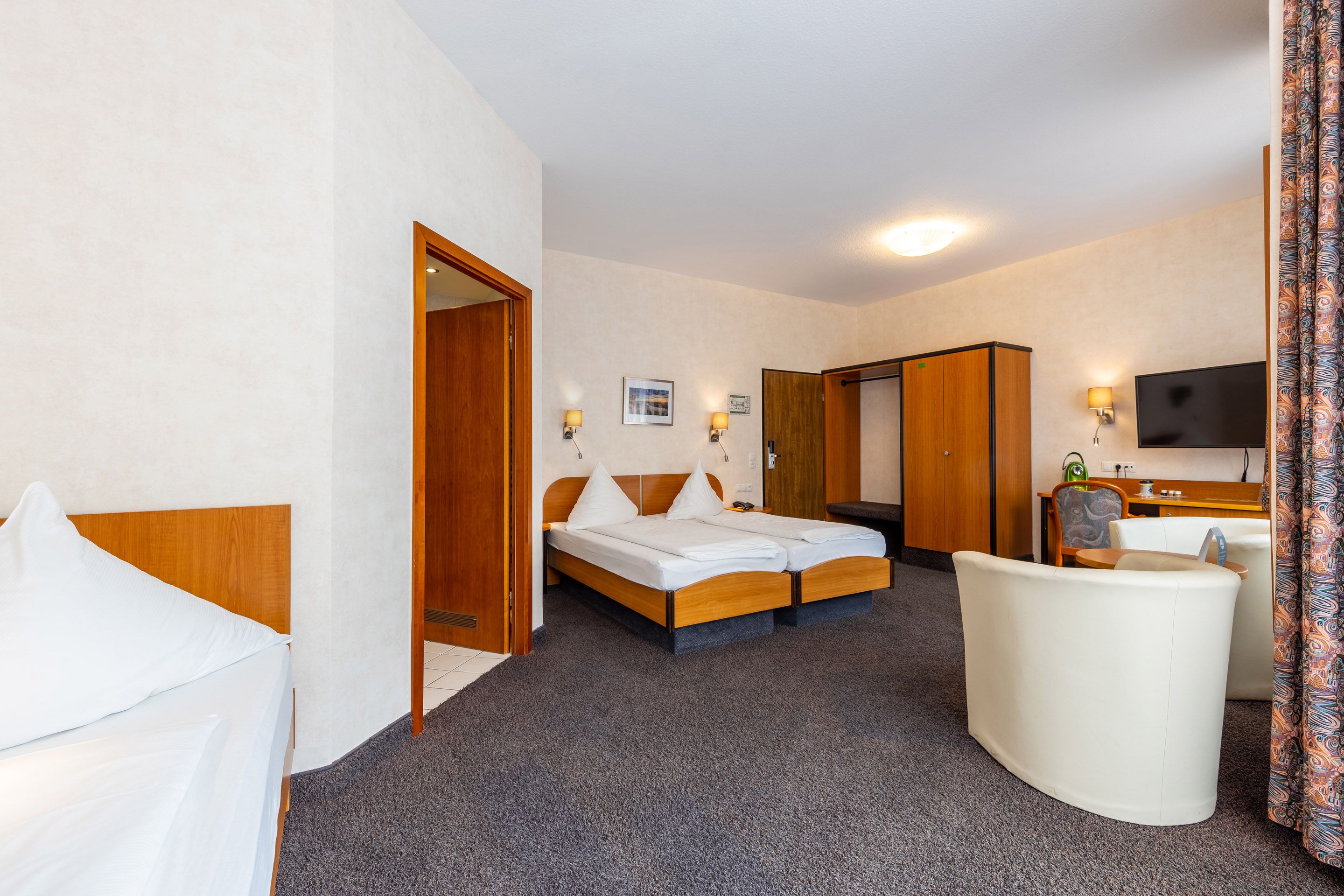 A hotel room with a bed, a desk, a chair, and a television.