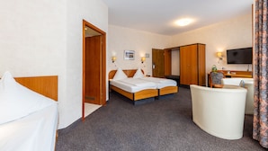 Ein Hotelzimmer mit Bett, Schreibtisch, Stuhl und Fernseher.