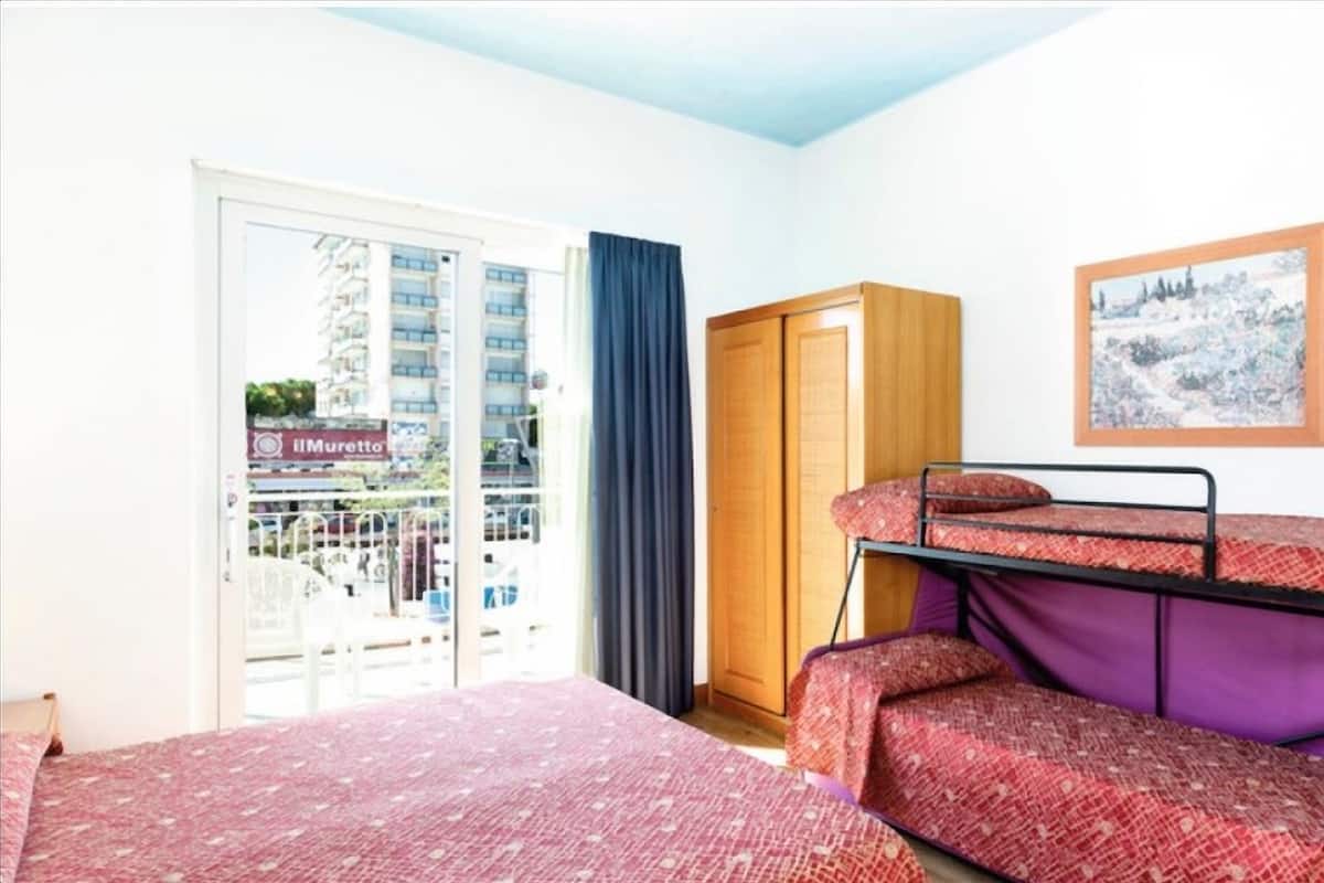 A room with a bunk bed, a wardrobe, a sliding glass door to the outside, and a framed picture on the wall.