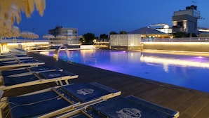 A swimming pool area with lounge chairs and a water feature. - Principe Palace (Jesolo)