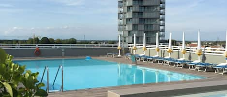 Una piscina al aire libre, una piscina en la azotea, tumbonas