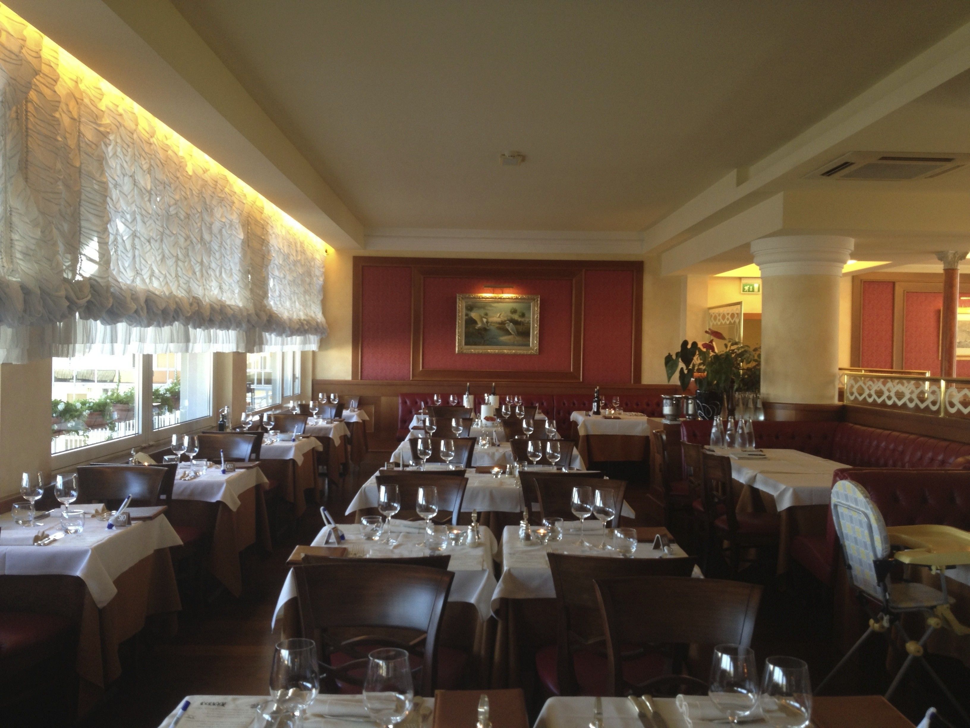Ein Restaurantinnenraum mit mehreren Tischen, Stühlen und einem großen Fenster mit Blick.