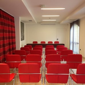 A conference room with red chairs, a long table, and a large window. - Delfina Palace (Foligno)