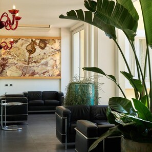 A modern living room with a black leather sofa, a glass coffee table, and a large abstract painting on the wall. - Delfina Palace (Foligno)